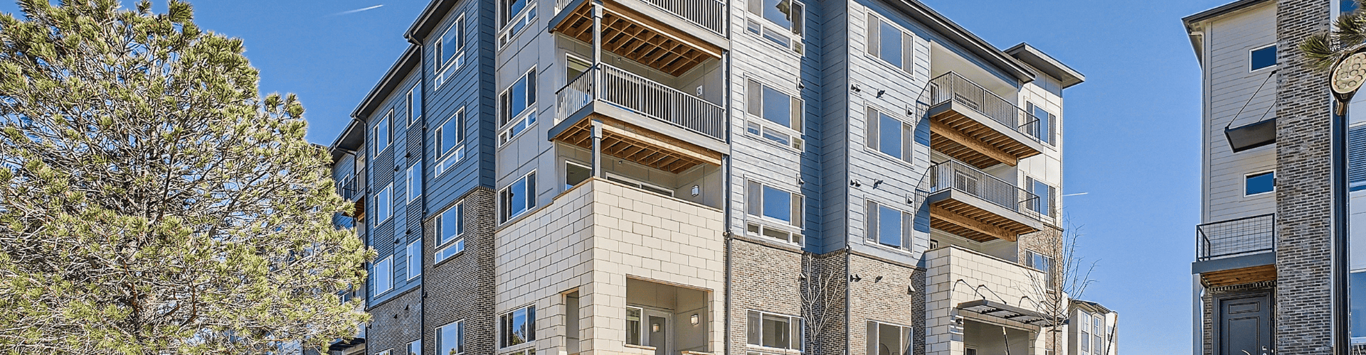A building with balconies and a tree in front.