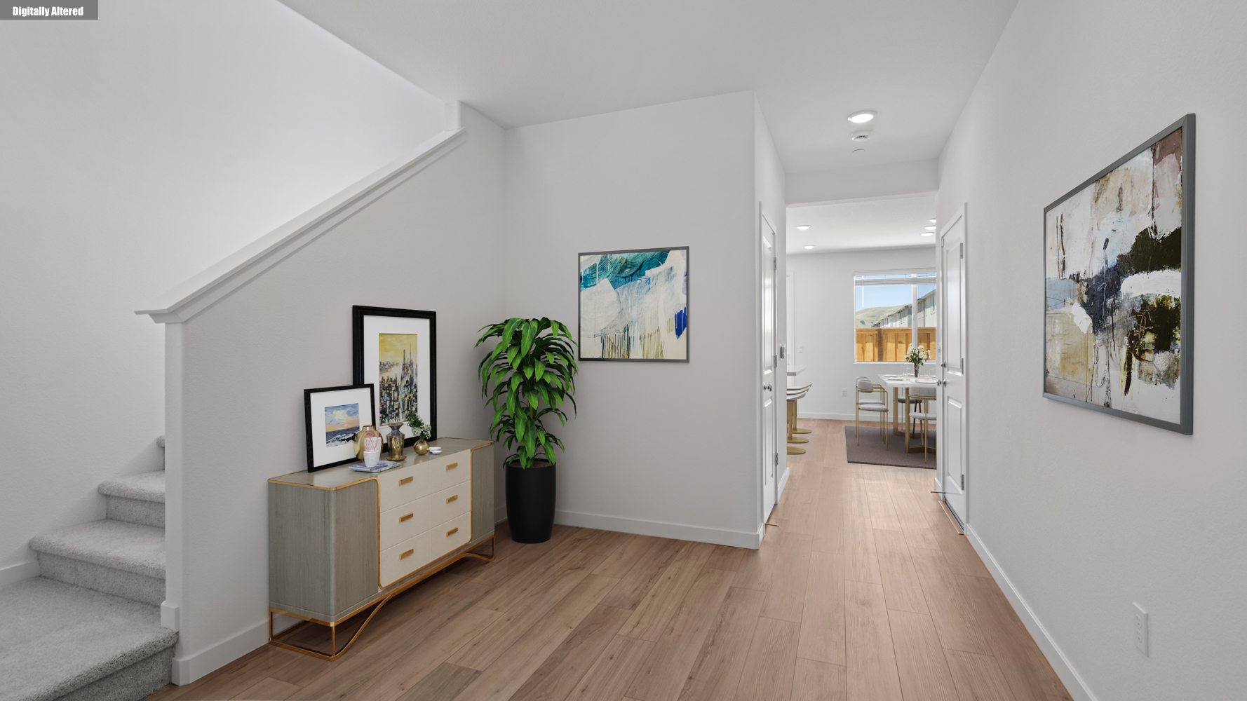A room with white walls and a wood floor with a plant on it.