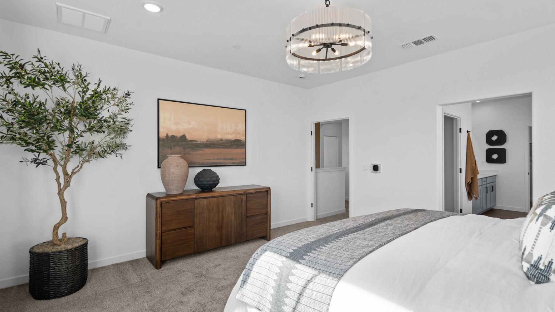 A bedroom with a bed and a plant.