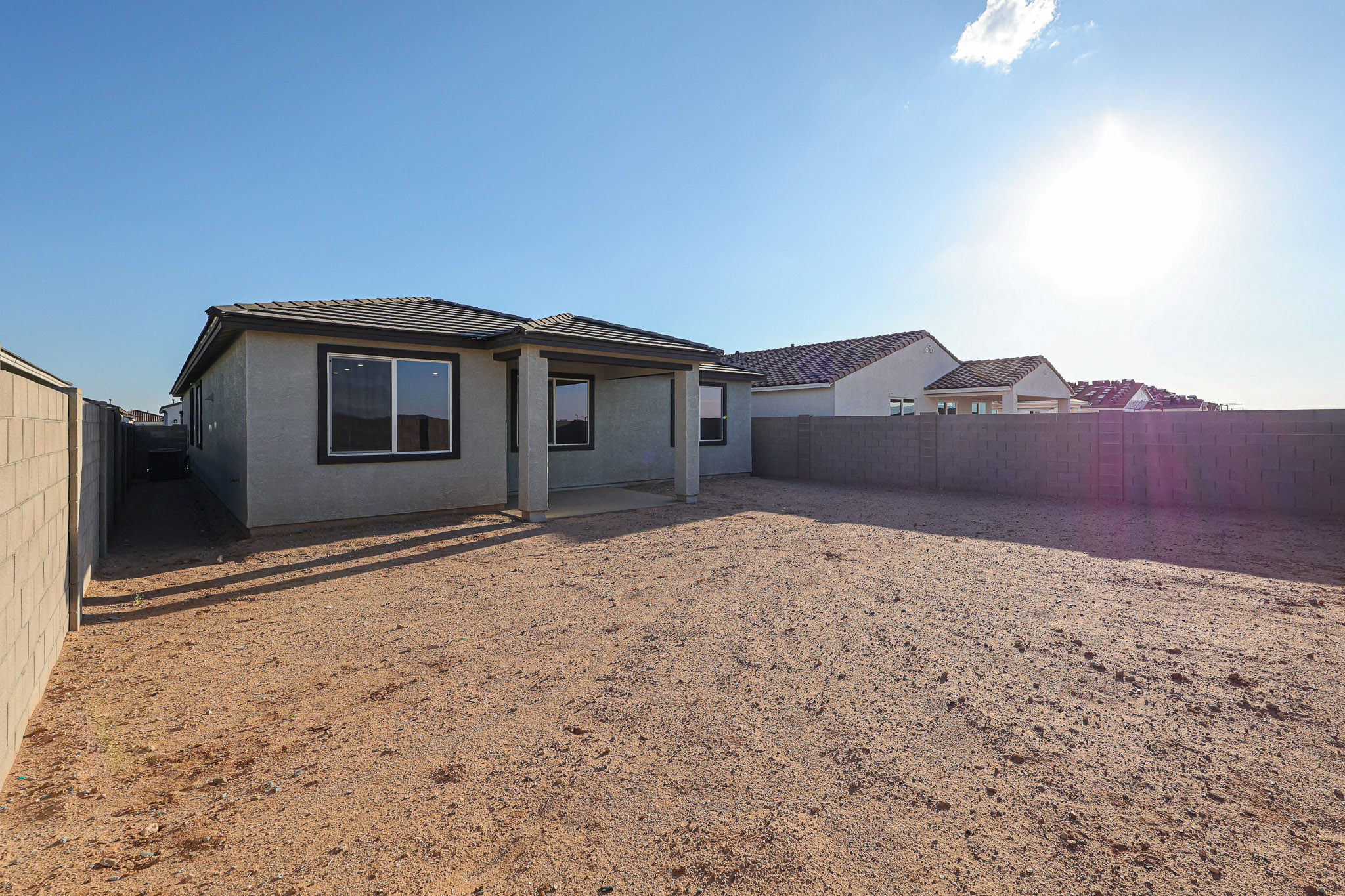 A dirt yard with a house in the background.