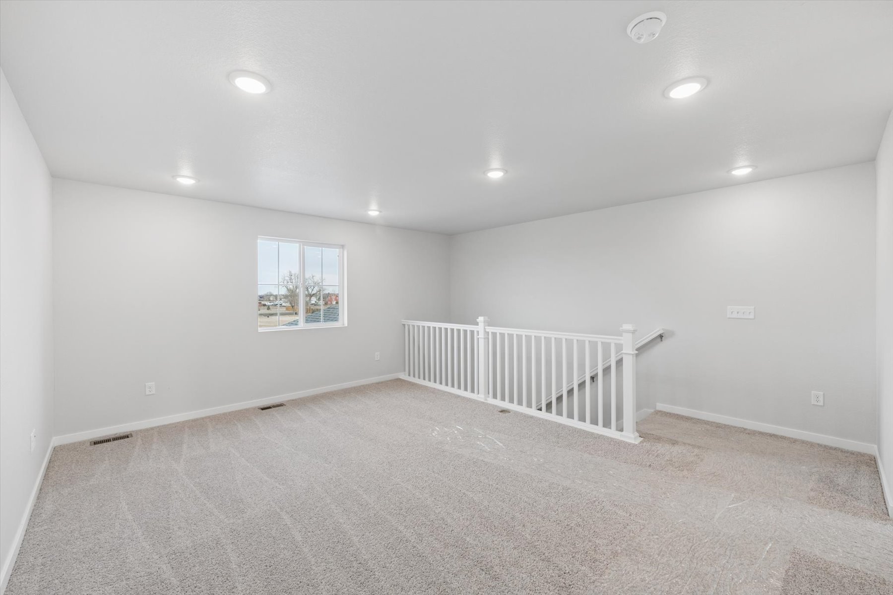 A room with a white railing and a white wall with a window.