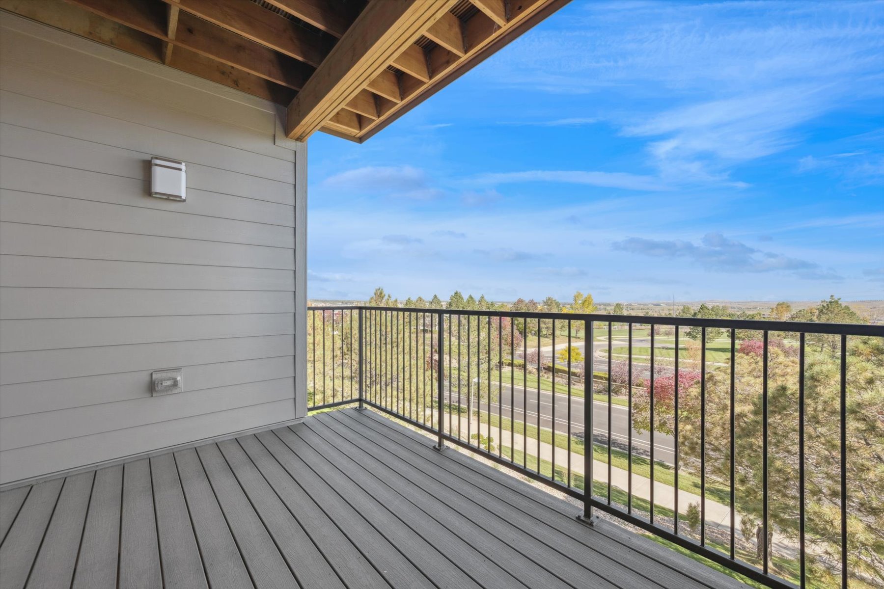 A deck with a railing and a building with a view of the ocean.