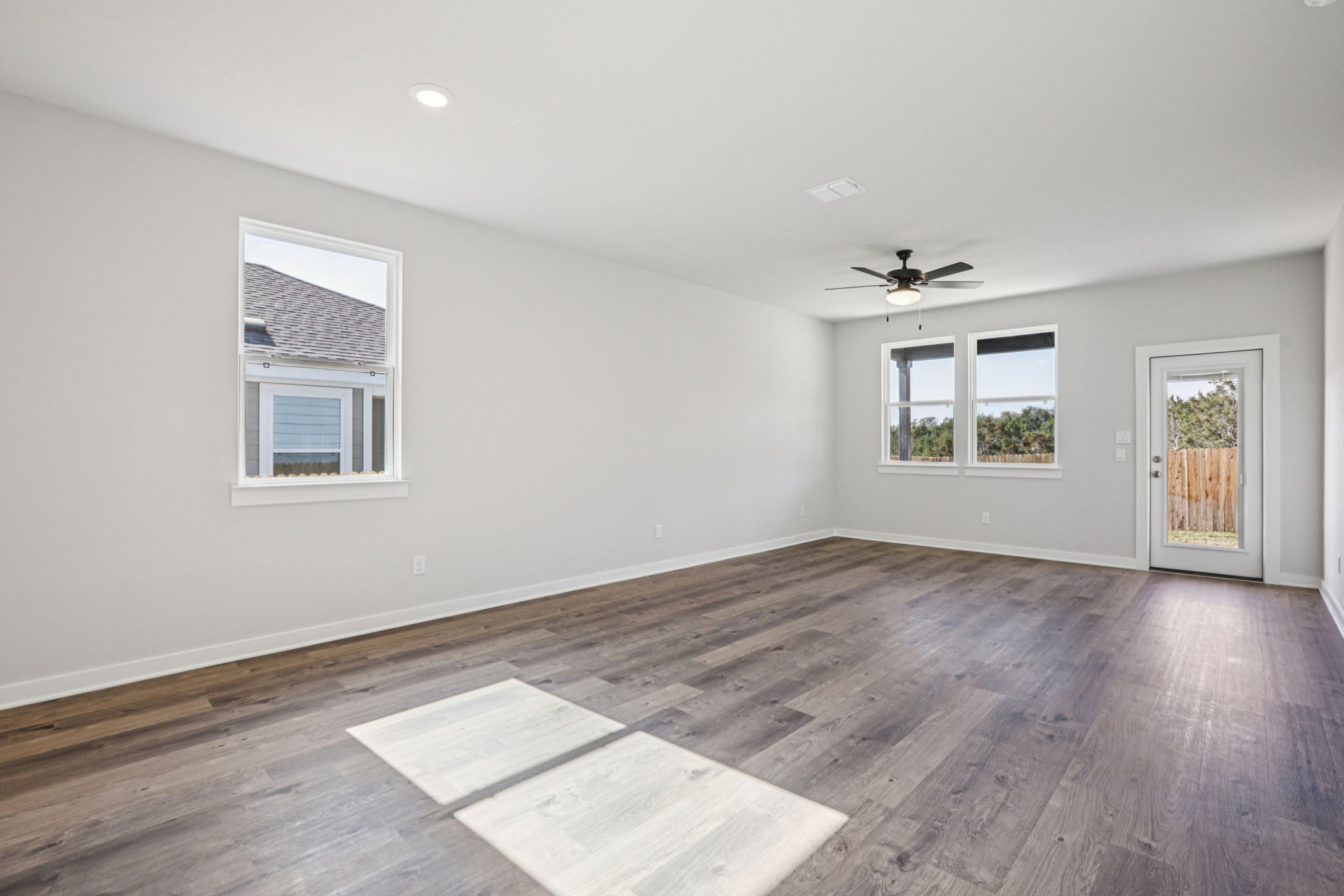 A room with a wood floor and a wood floor with a fan.