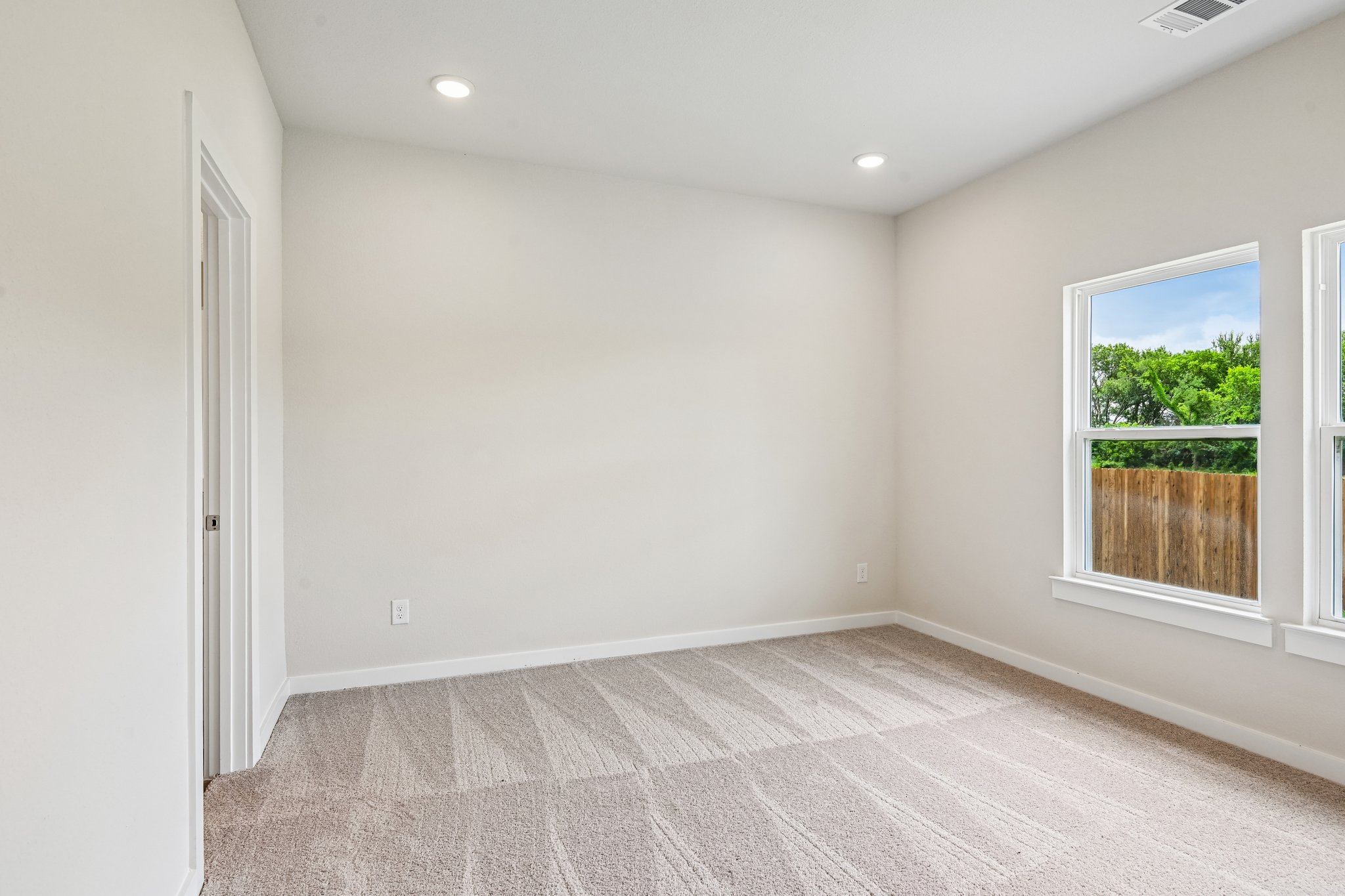 A room with a carpet and windows.