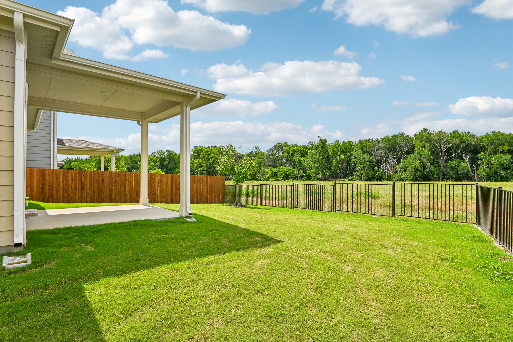 A backyard with a fence and a covered area.