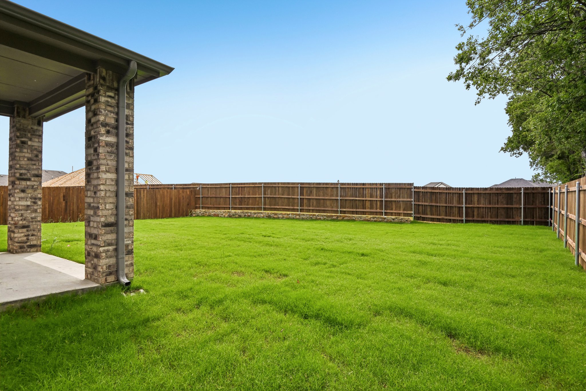 A grassy area with a fence and a building in the background.