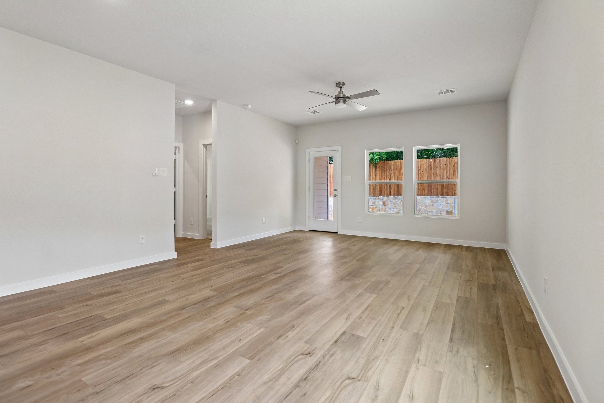 A room with a wood floor and a ceiling fan.