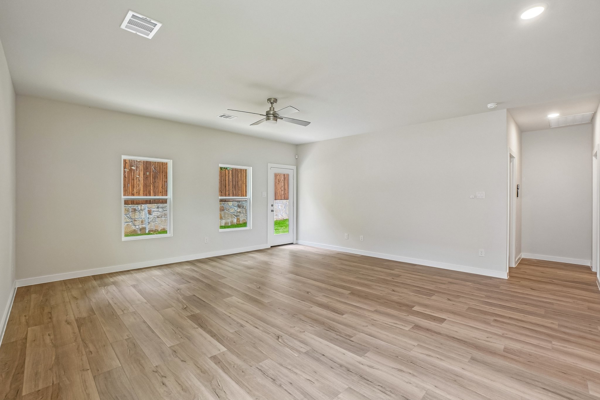 A room with a wood floor and a ceiling fan.