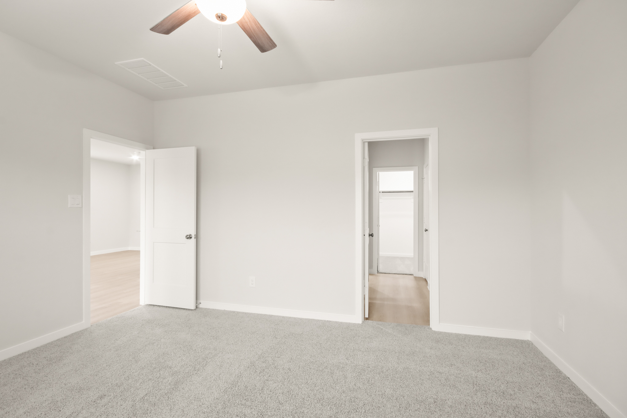 A room with a ceiling fan and a door.