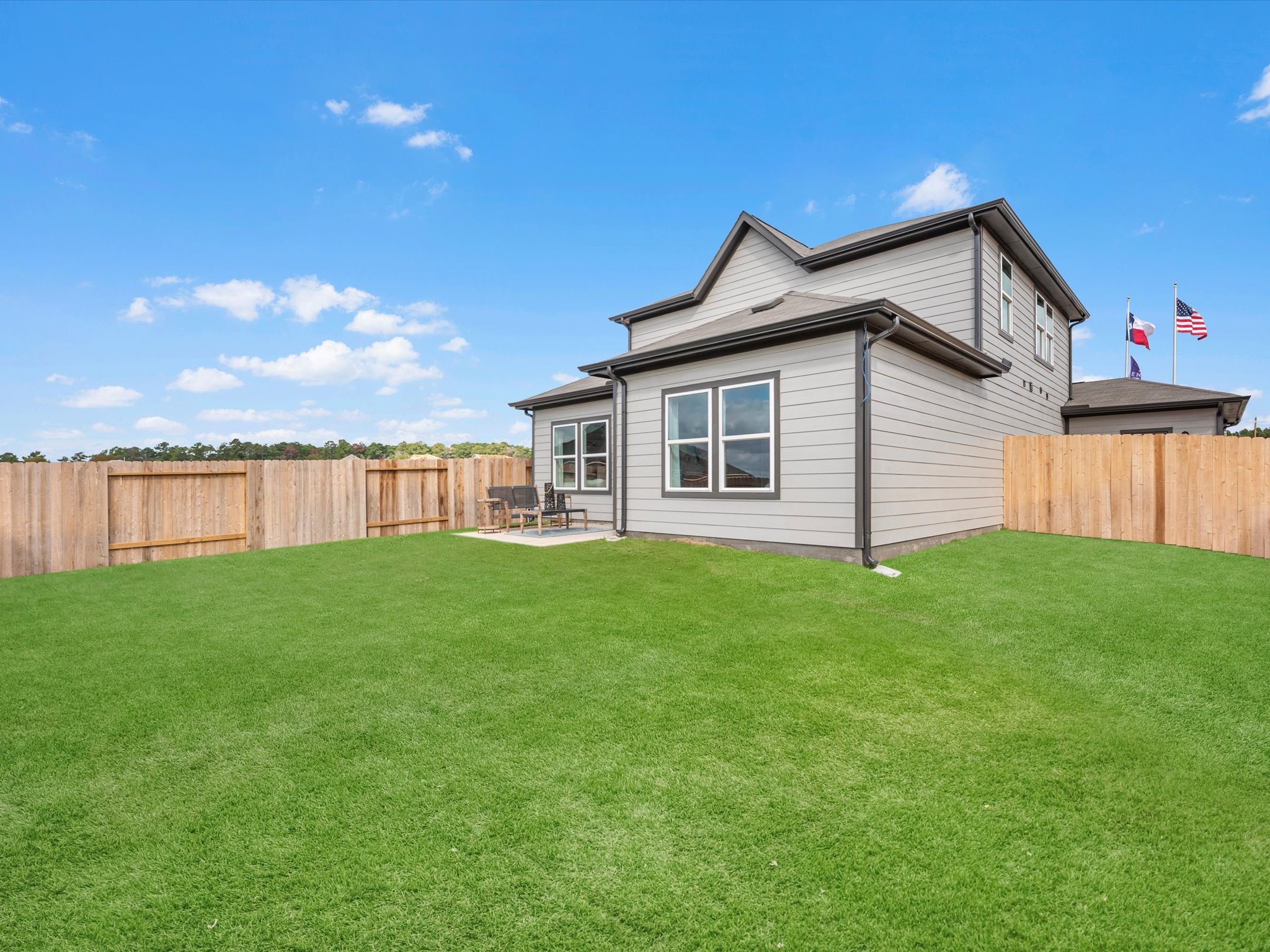 A house with a fence and a lawn in front of it.
