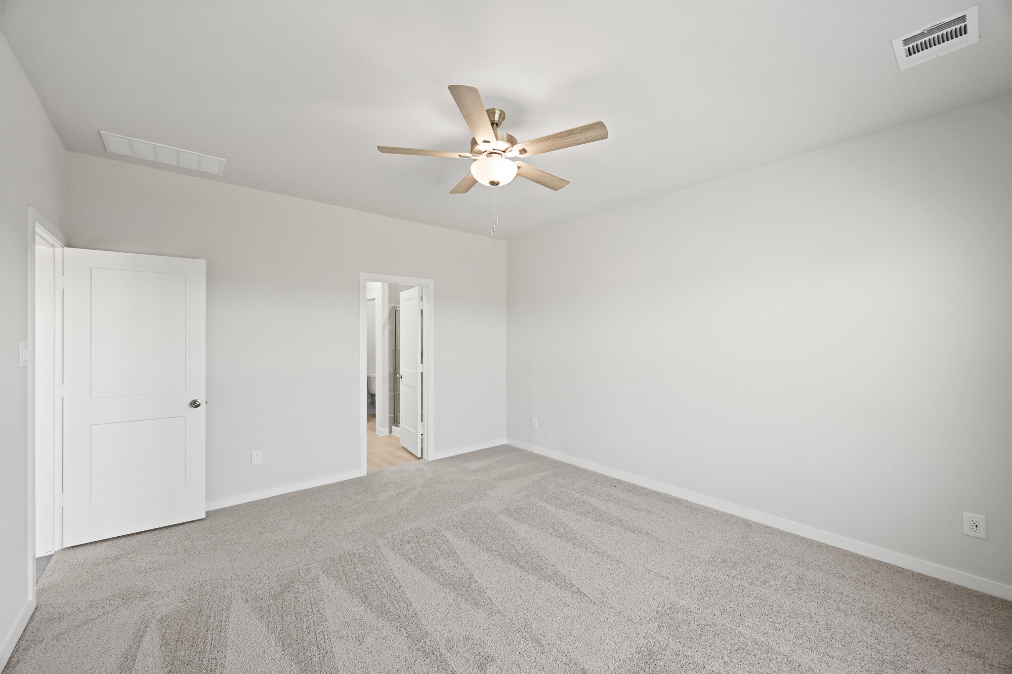 A room with a ceiling fan and a carpet.