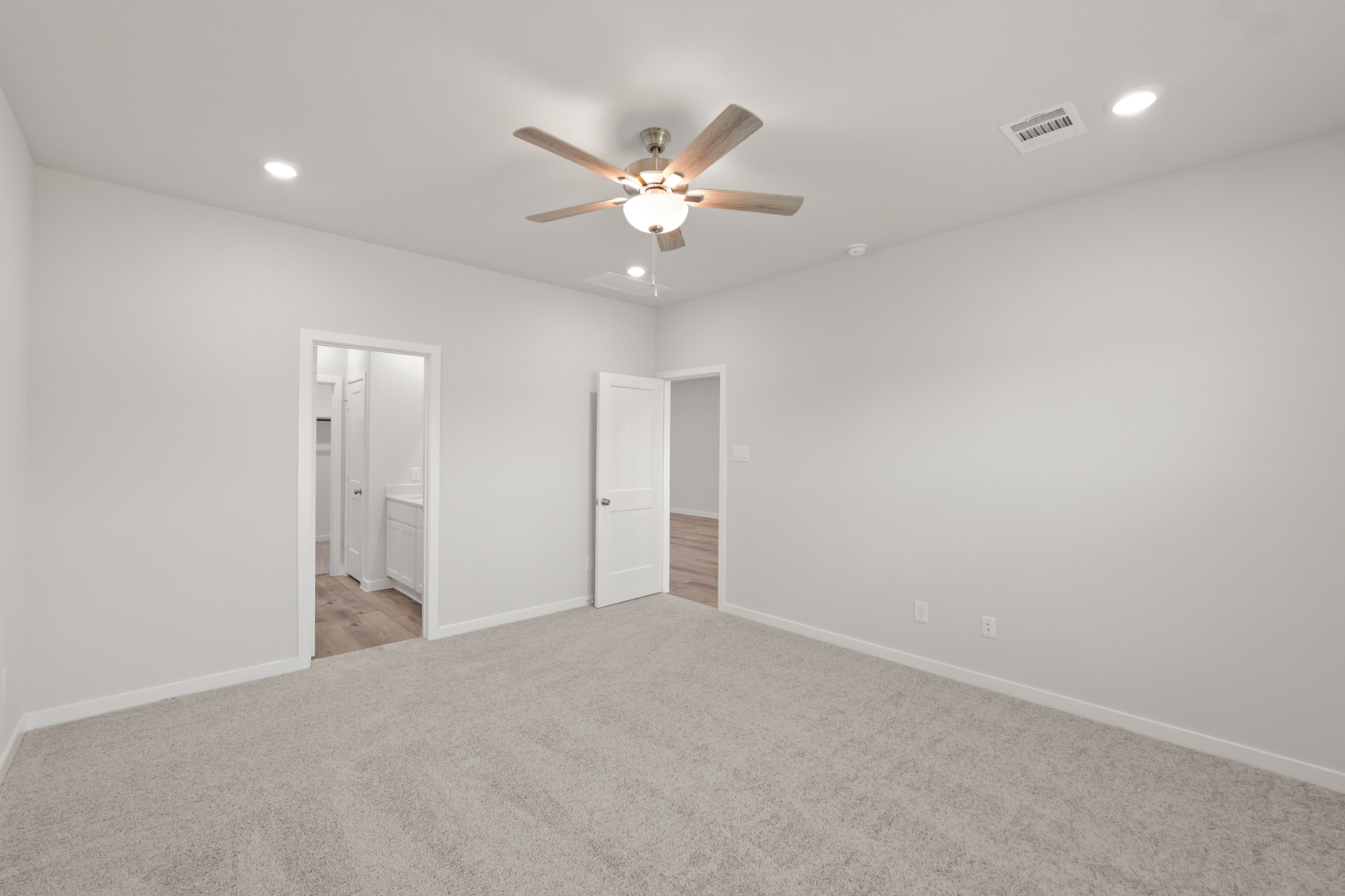A room with a ceiling fan and a carpet.