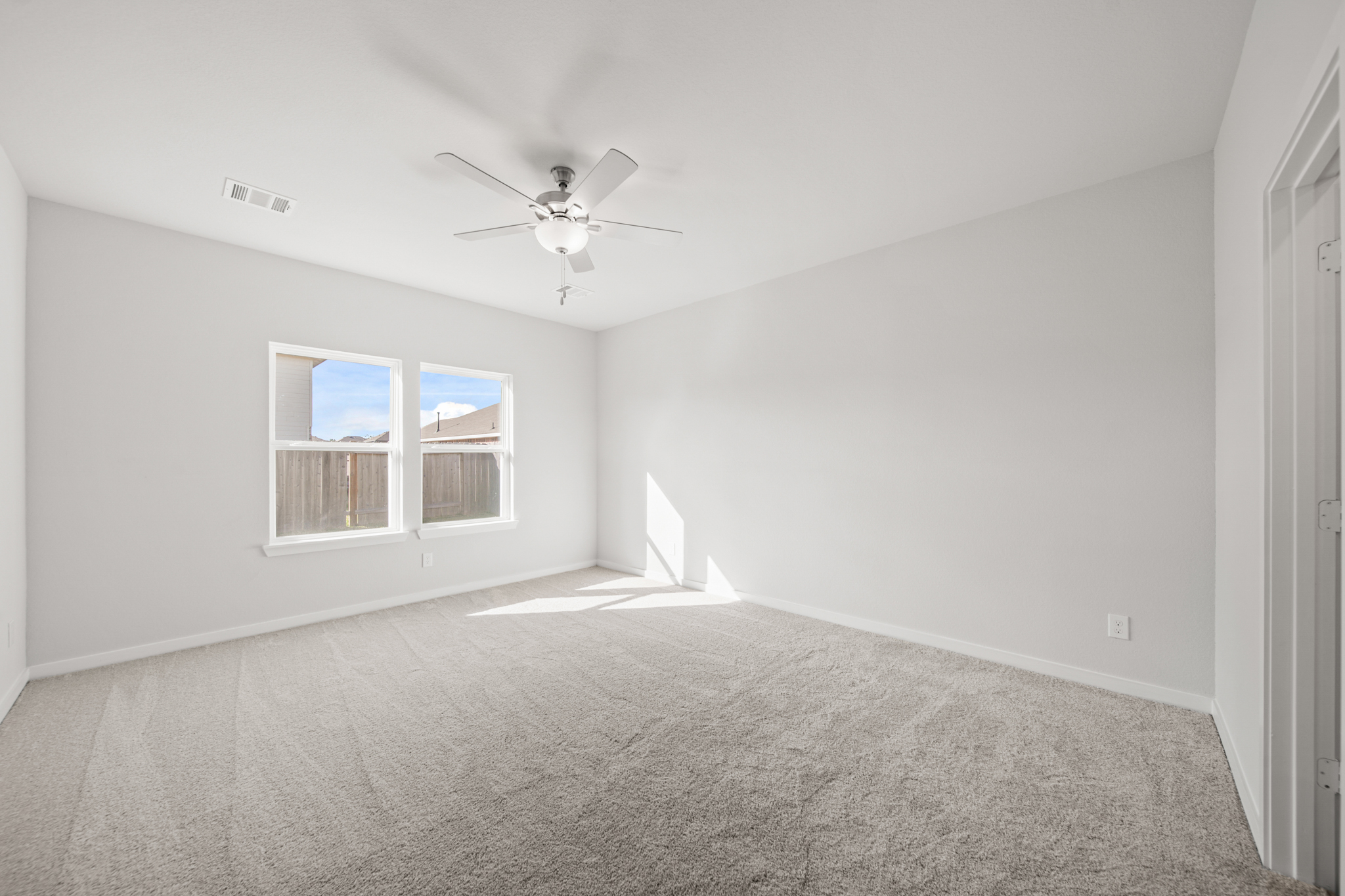 A room with a ceiling fan and a carpet.