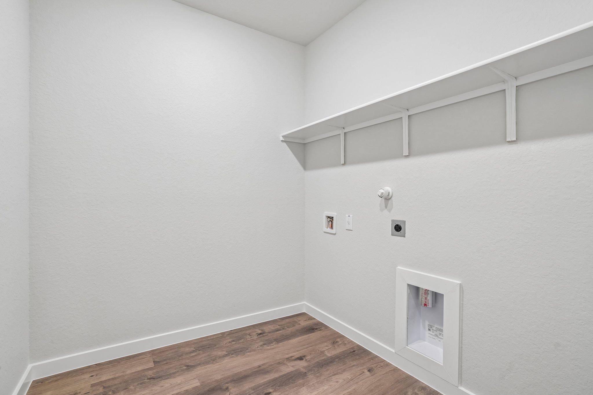 A white room with a wood floor and white walls.
