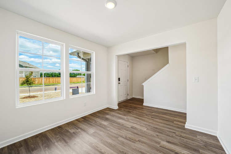 A room with a wood floor and a window with a view of the ocean.