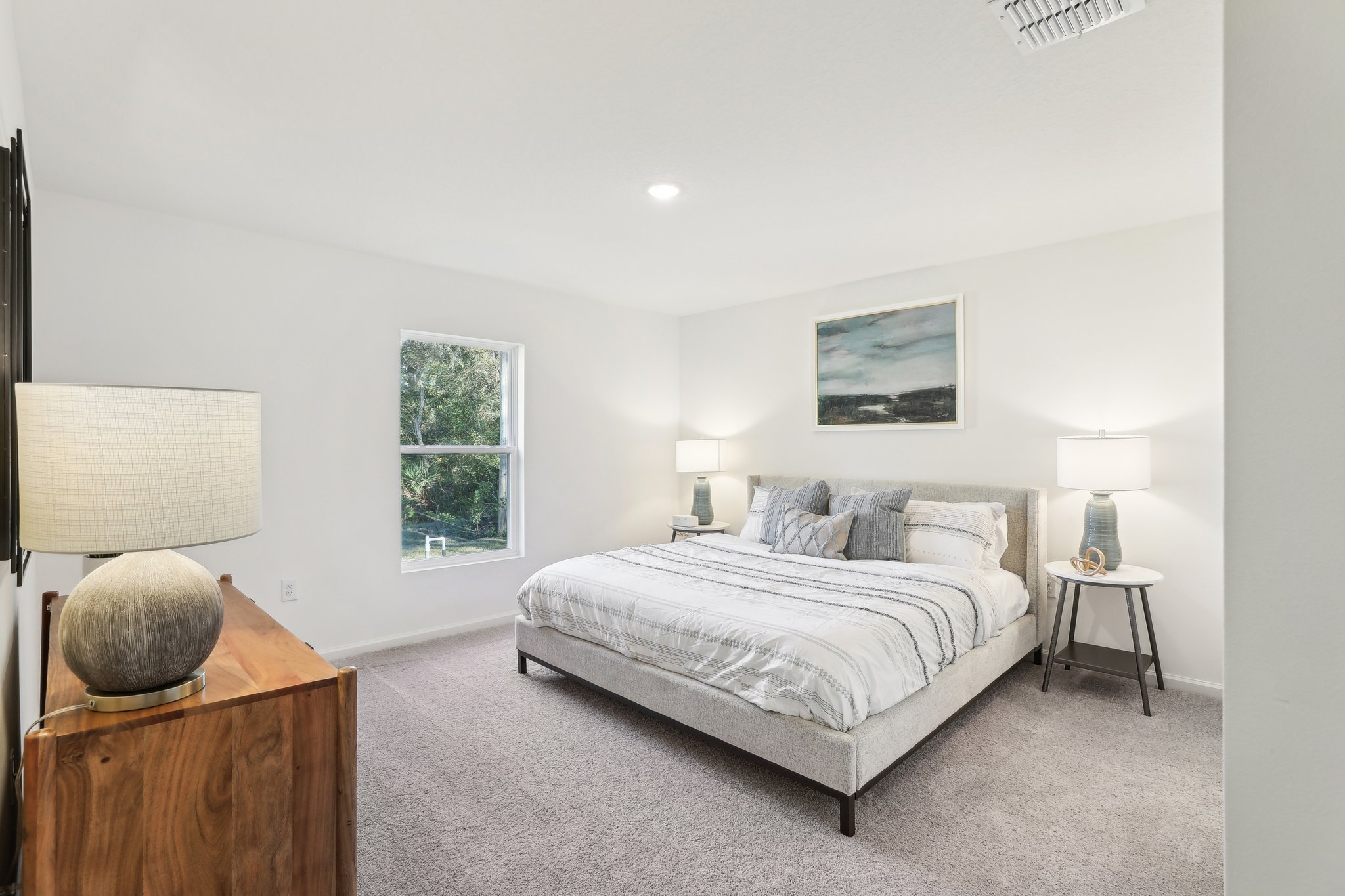 A bedroom with a bed and lamps.